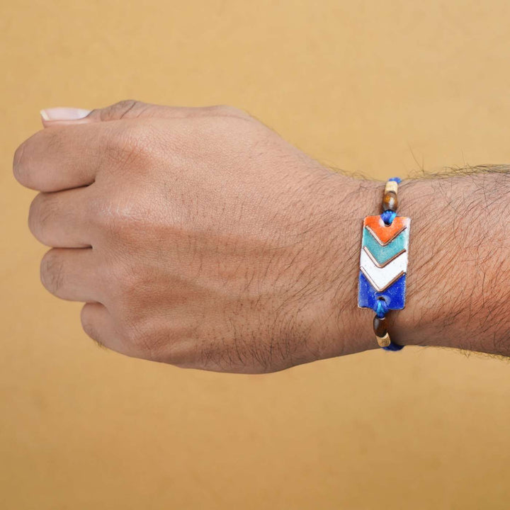 Handmade Arrows Copper Enamel Rakhi With Chocolates And Roli Chawal - Worn on Model's Wrist