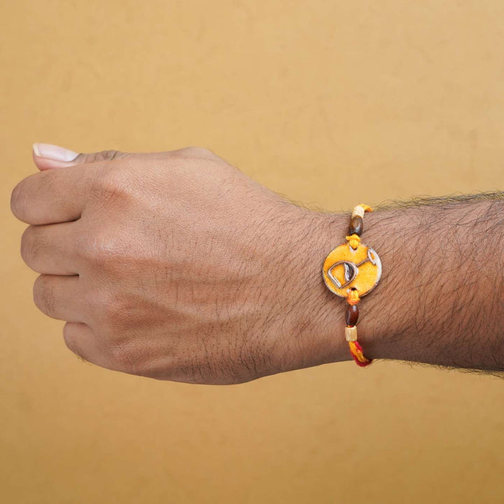 Handmade Wine O Clock Copper Enamel Rakhi With Chocolates And Roli Chawal - Worn on wrist example