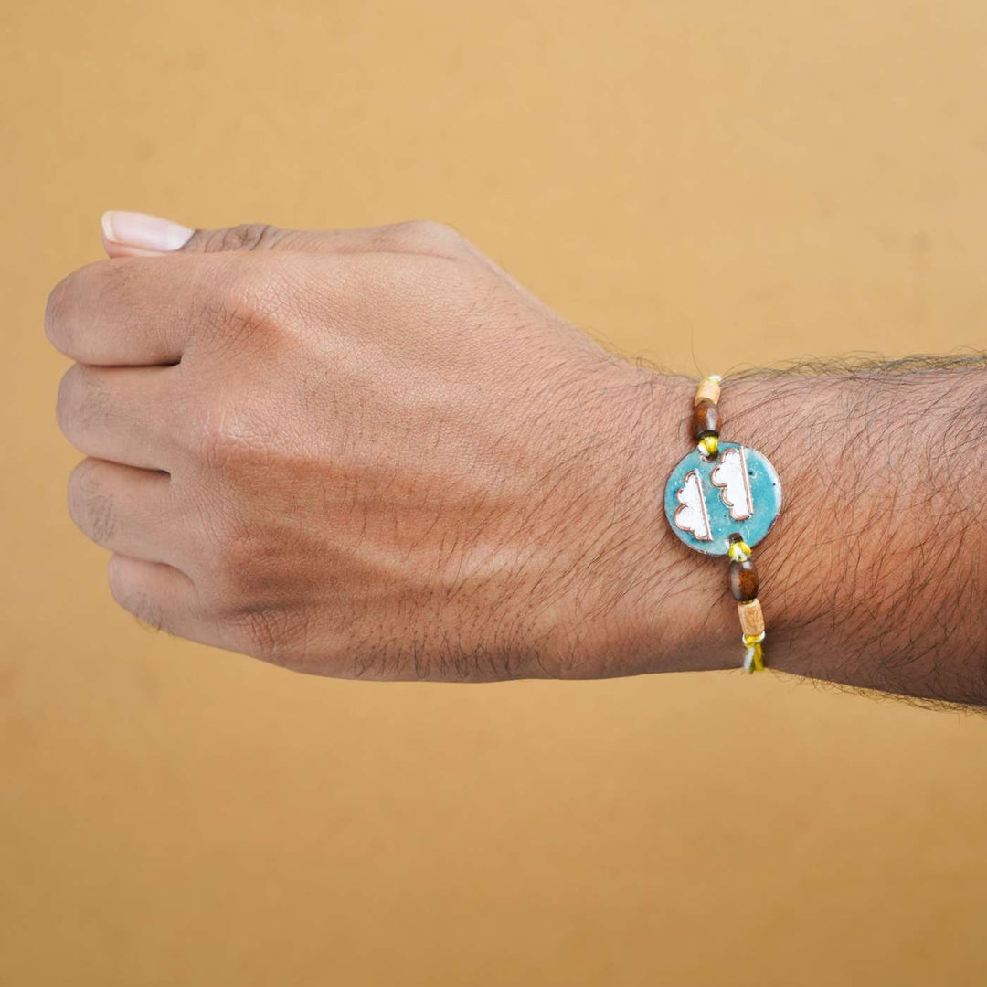 Handmade Baadal Blue Copper Enamel Rakhi With Chocolates And Roli Chawal - Worn Rakhi on wrist