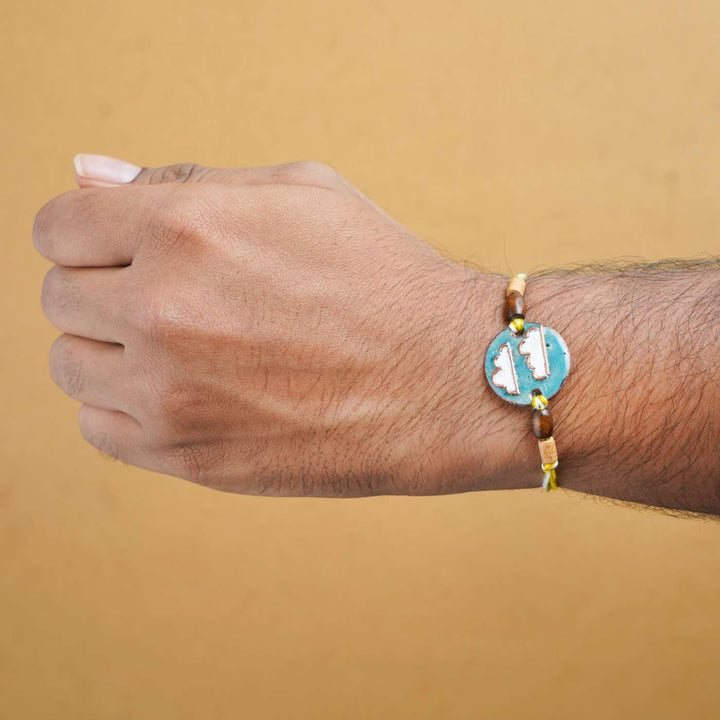 Handmade Baadal Blue Copper Enamel Rakhi With Chocolates And Roli Chawal - Worn Rakhi on wrist
