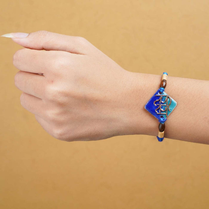 Handmade Sis Blue Copper Enamel Rakhi With Chocolates And Roli Chawal - Rakhi worn on wrist