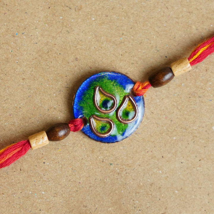 Handmade Morpankh Copper Enamel Rakhi With Chocolates And Roli Chawal - Close-up of blue circular bracelet
