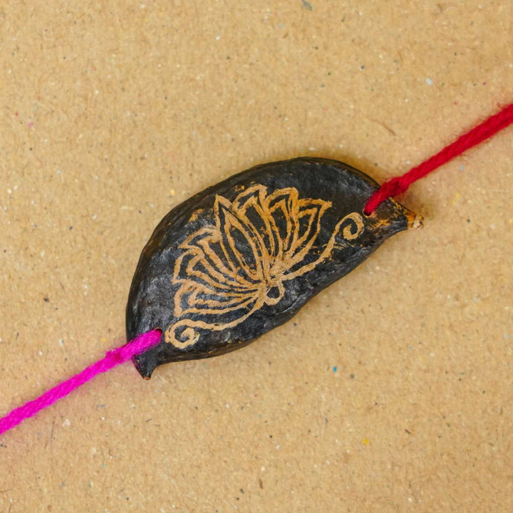 Handmade Plantable Painted Lotus Seed Rakhi With Roli Chawal - Close-up of Rakhi centerpiece