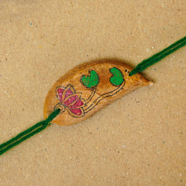 Handmade Plantable Magenta Lotus Seed Rakhi With Roli Chawal - Close-up of decorated rakhi strand