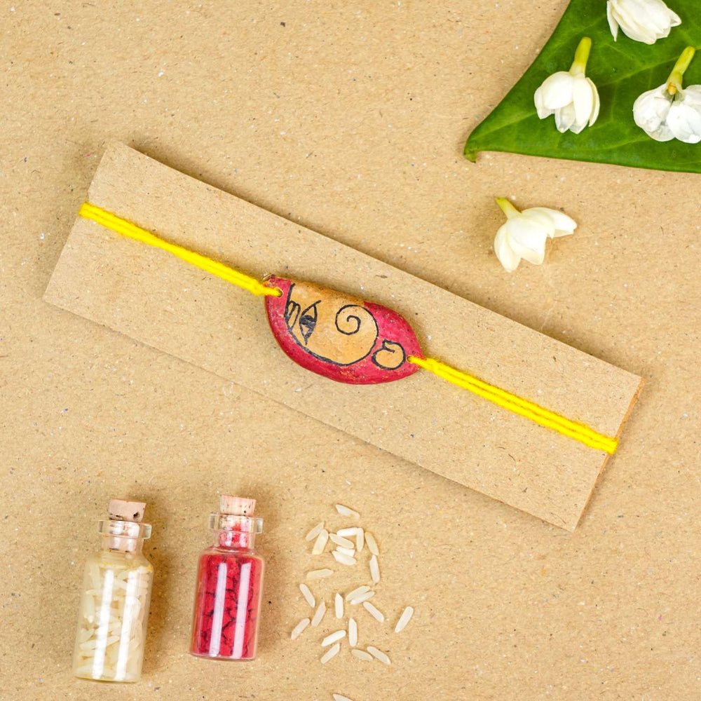 Handmade Plantable Ganesha Seed Rakhi With Roli Chawal - Flat lay with bracelet and flowers