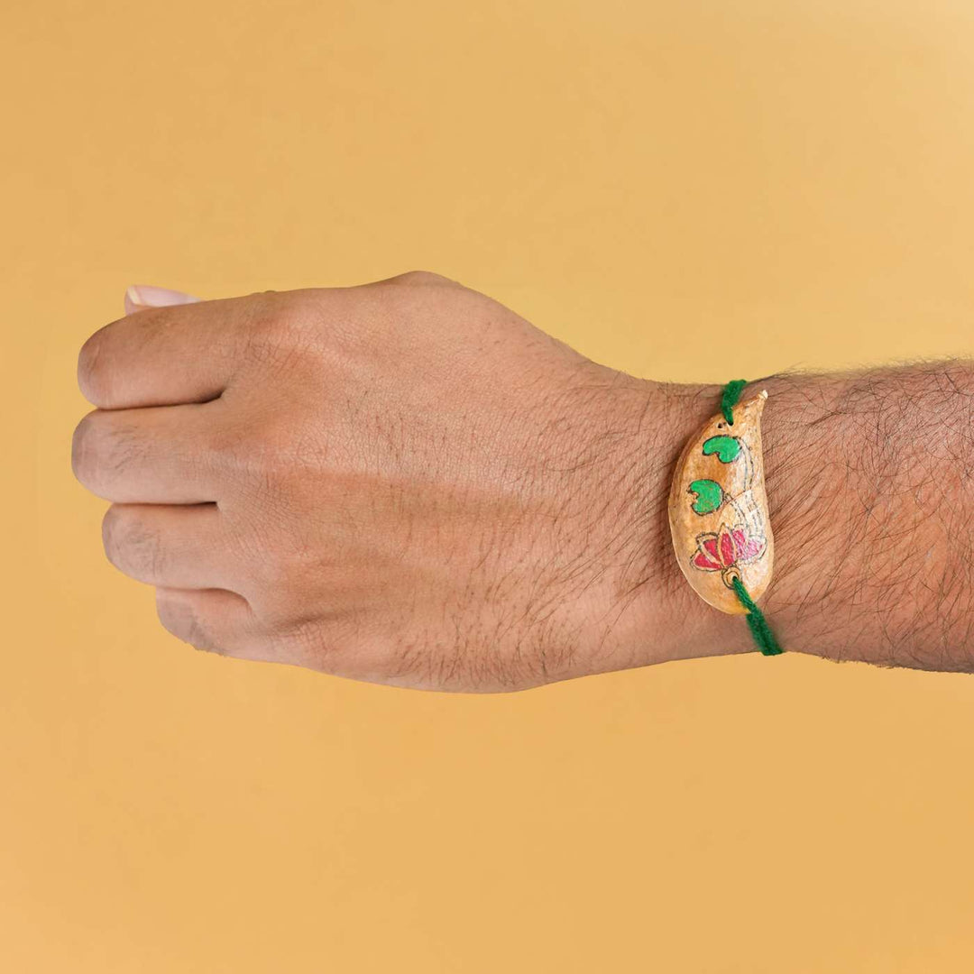 Handmade Plantable Magenta Lotus Seed Rakhi With Roli Chawal - Rakhi worn on wrist