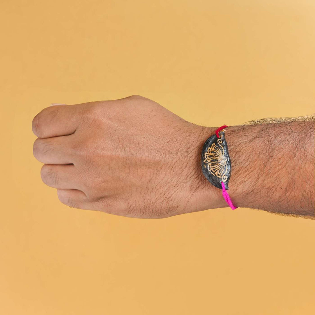 Handmade Plantable Painted Lotus Seed Rakhi With Roli Chawal - Rakhi worn on wrist