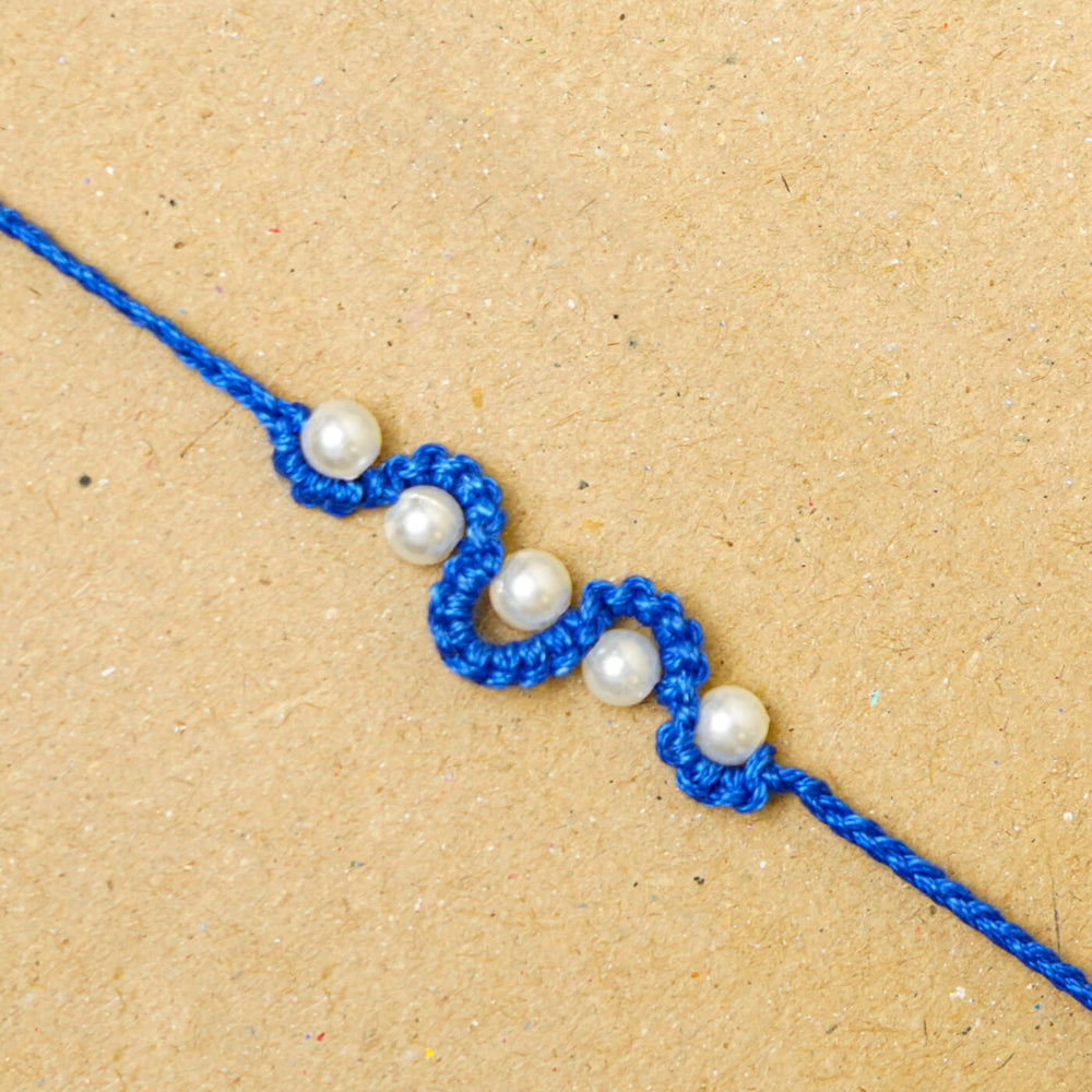 Handmade Macrame Five Pearl Rakhi With Roli Chawal - Close-up of blue string bracelet