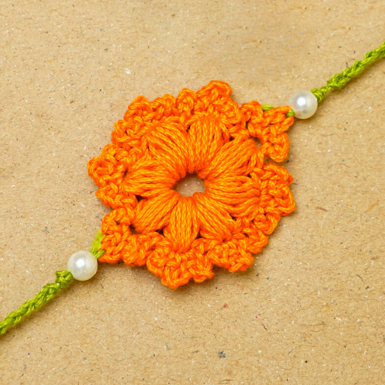 Handmade Crochet Floral Cotton Rakhi With Roli Chawal - Close-up of orange Rakhi
