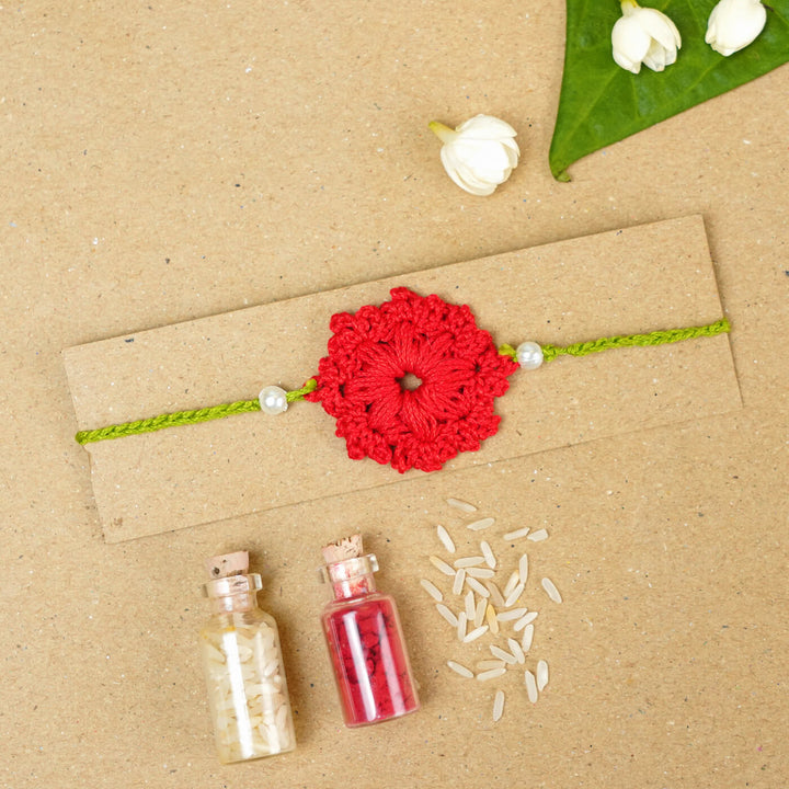 Handmade Crochet Floral Cotton Rakhi With Roli Chawal - Red Rakhi on packaging board