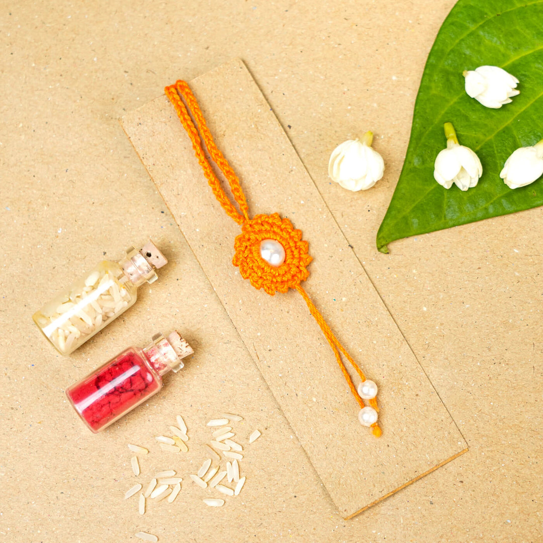 Handmade Crochet Round Pearl Cotton Lumba Rakhi For Bhabhi With Roli Chawal - Flat lay with decorative elements (9)