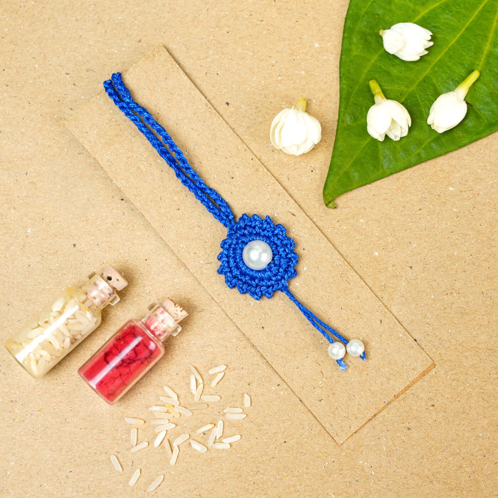 Handmade Crochet Round Pearl Cotton Lumba Rakhi For Bhabhi With Roli Chawal - Flat lay with decorative elements