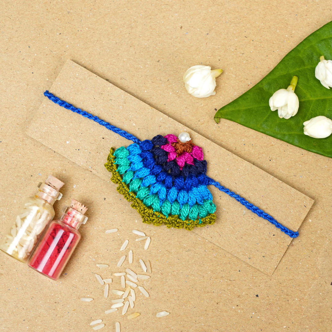 Handmade Crochet Peacock Cotton Rakhi With Roli Chawal - Flat lay with rakhi and decorations