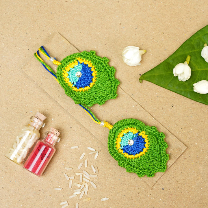Handmade Crochet Peacock Feather Cotton Lumba Rakhi For Bhabhi With Roli Chawal - Laid Flat with Decorative Items