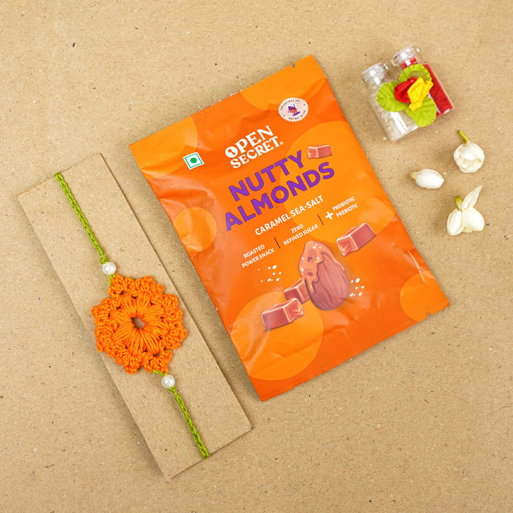 Handmade Crochet Floral Cotton Rakhi With Roli Chawal - Flat lay with snack pack