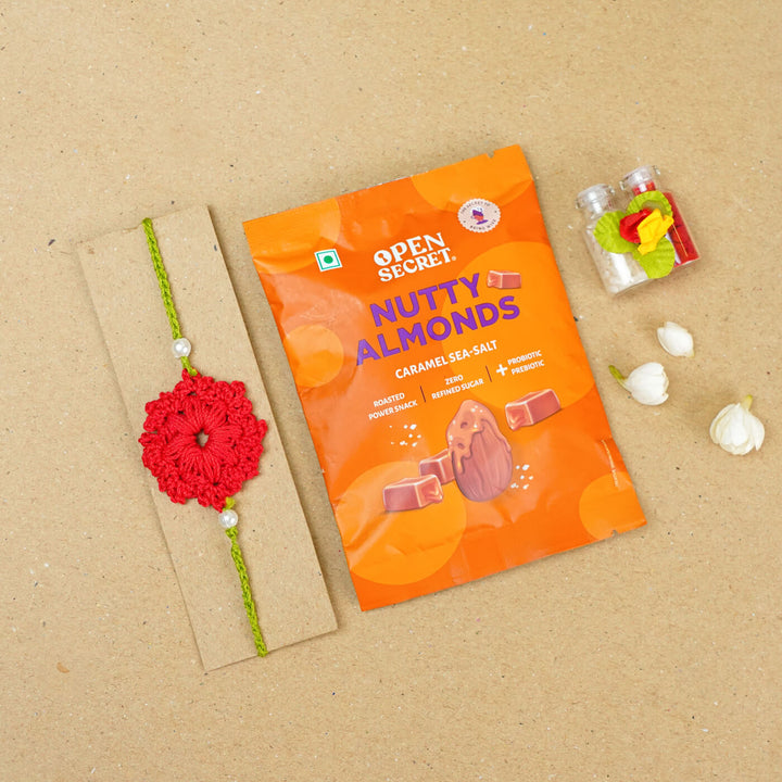 Handmade Crochet Floral Cotton Rakhi With Roli Chawal - Flat lay with snack pack (15)