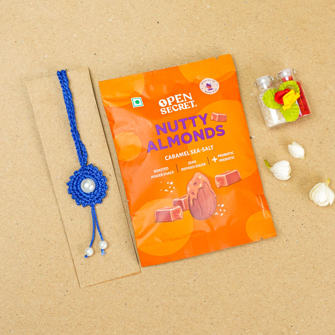 Handmade Crochet Round Pearl Cotton Lumba Rakhi For Bhabhi With Roli Chawal - Flat lay with snack pack