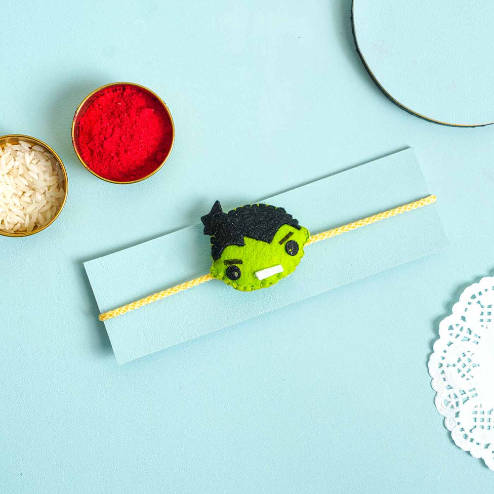 Handmade Hulk Felt Kids Rakhi With Roli Chawal - Product on card with traditional items