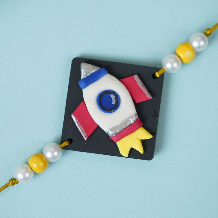 Handmade Miniature Clay Space Rocket Kids Rakhi With Roli Chawal - Close-up of Rocket Charm