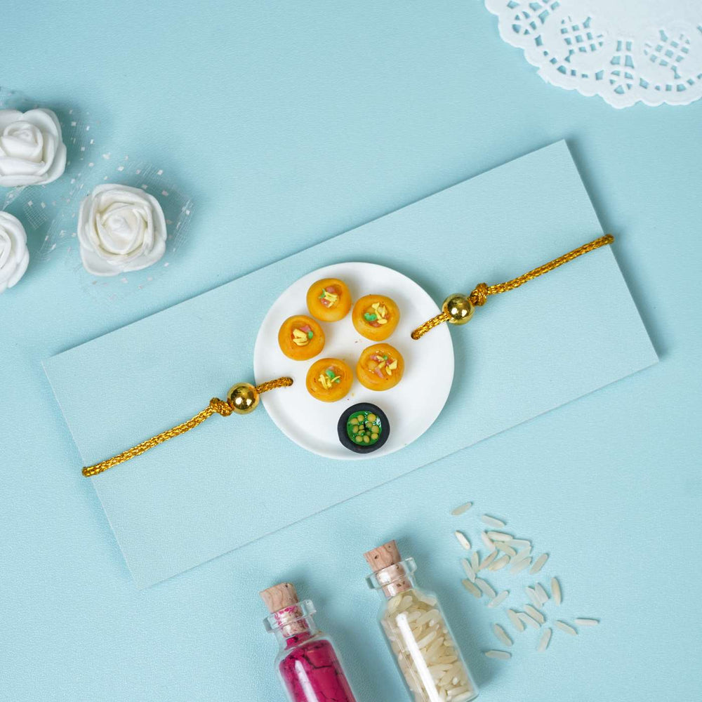 Handmade Miniature Clay Pani Puri Rakhi With Roli Chawal - Flat lay of Rakhi on envelope