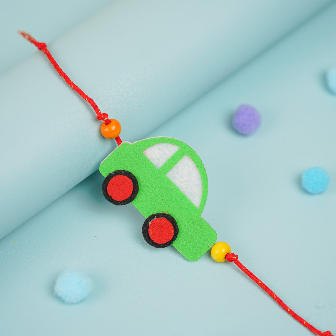 Customized Handmade Beaded Car Theme Pom Pom Felt Rakhi With Roli Chawal For Kids - Close-up of green car charm