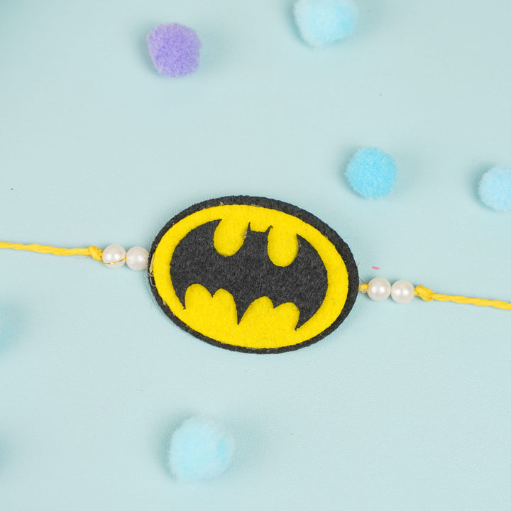 Handmade Beaded Batman Theme Pom Pom Felt Rakhi With Roli Chawal For Kids - Front View on Flat Surface