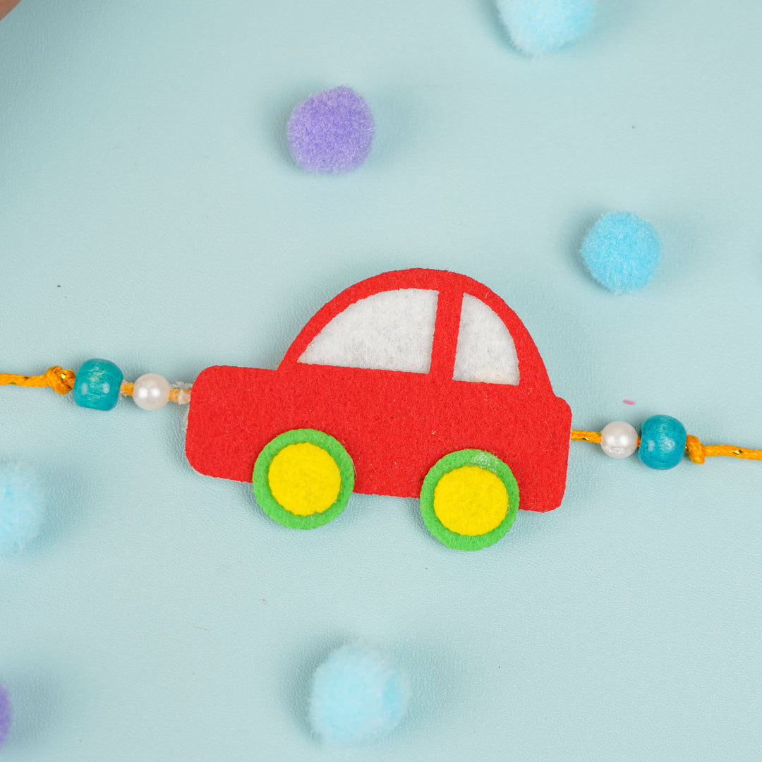 Customized Handmade Beaded Car Theme Pom Pom Felt Rakhi With Roli Chawal For Kids - Front view of red car charm
