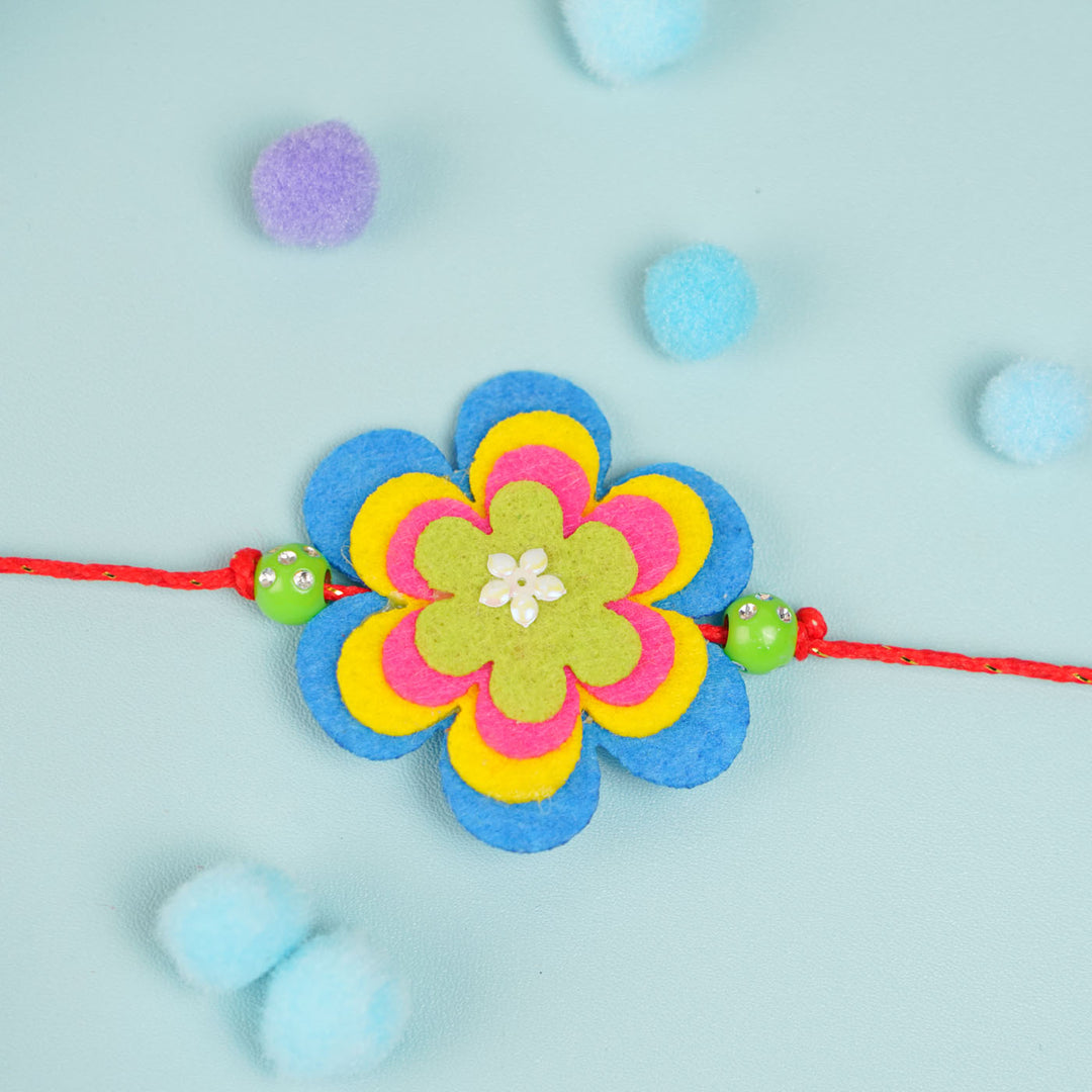 Handmade Beaded Flower Theme Pom Pom Felt Rakhi With Roli Chawal For Kids - Centered Flat Lay View