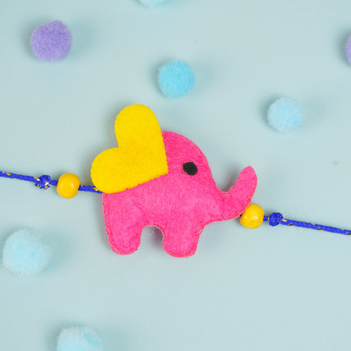 Customized Handmade Beaded Elephant Theme Pom Pom Felt Rakhi With Roli Chawal For Kids - Close-up of Pink Elephant Charm