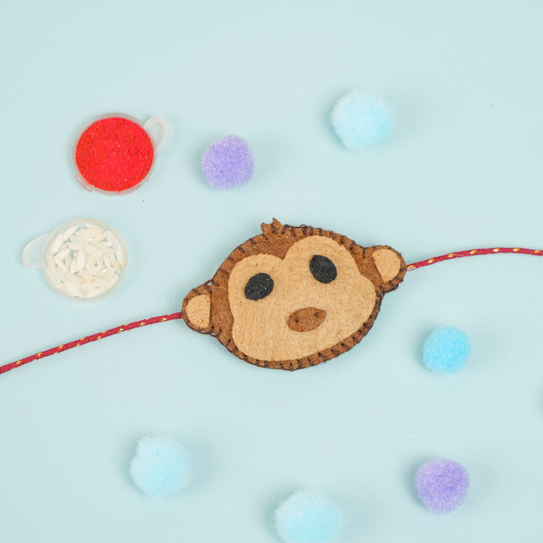 Handmade Beaded Monkey Theme Pom Pom Felt Rakhi With Roli Chawal For Kids - Flat Lay with Decorative Elements
