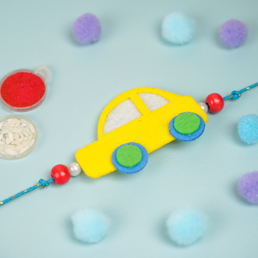 Customized Handmade Beaded Car Theme Pom Pom Felt Rakhi With Roli Chawal For Kids - Top view of yellow car charm
