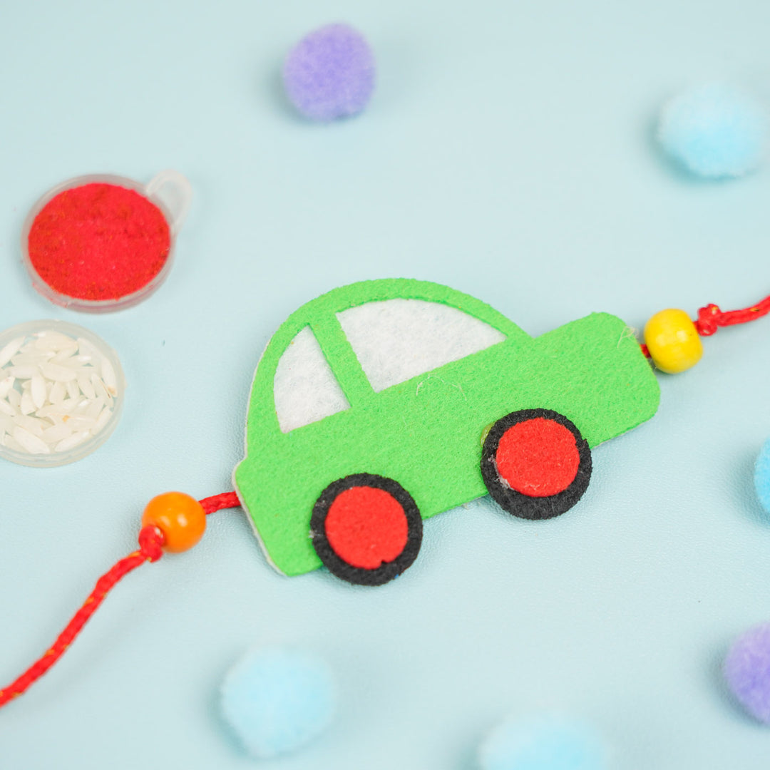 Customized Handmade Beaded Car Theme Pom Pom Felt Rakhi With Roli Chawal For Kids - Top view of green car charm