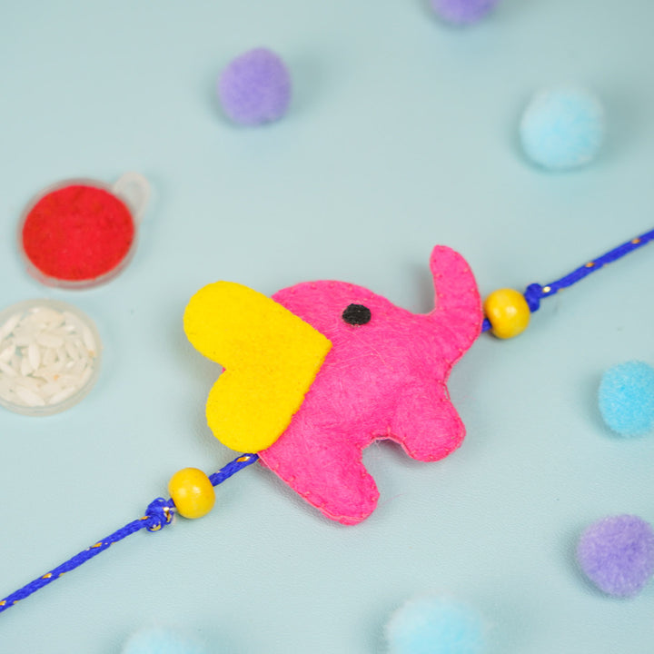 Customized Handmade Beaded Elephant Theme Pom Pom Felt Rakhi With Roli Chawal For Kids - Side View of Pink Elephant Charm