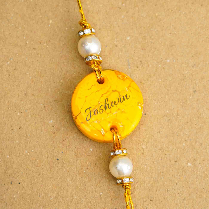 Personalized Handmade Yellow Resin Rakhi With Roli Chawal - Close-up of Name Personalization