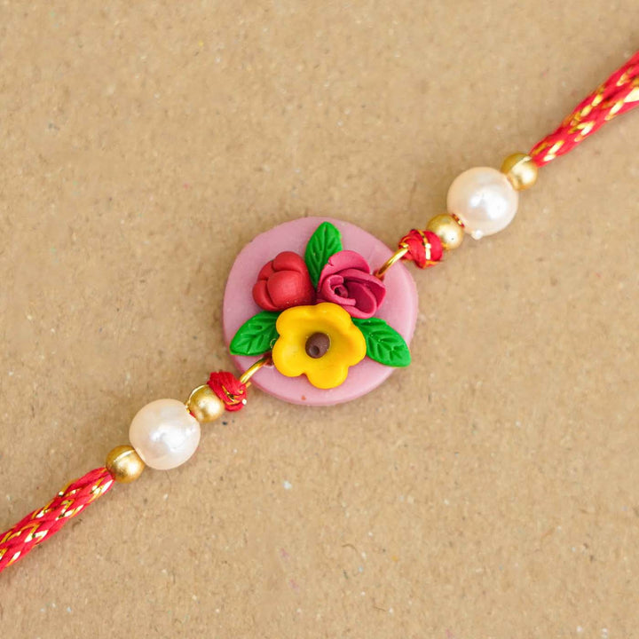 Handmade Miniature Clay Yellow And Red Floral Rakhi With Roli Chawal - Close-up of floral design