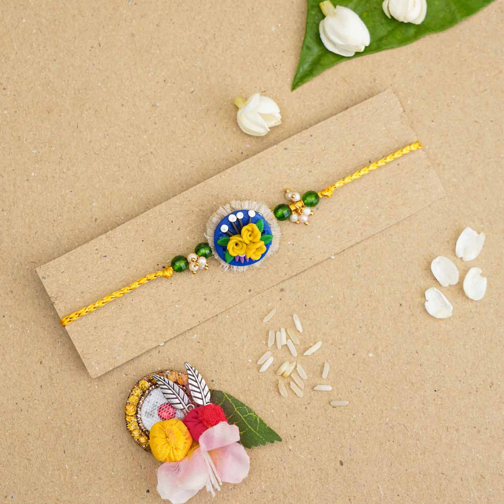 Handmade Miniature Clay Yellow And Blue Floral Rakhi With Roli Chawal - Bracelet on cardboard display