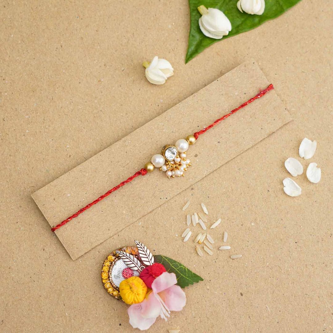 Handmade Kundan Red And White Beads Rakhi With Roli Chawal - Flat lay with packaging and decoration