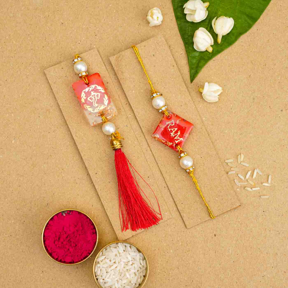 Personalized Handmade Red Resin Bhaiya Bhabhi Rakhi With Roli Chawal Set Of 2 - Rakhis on cardboard with rice and kumkum