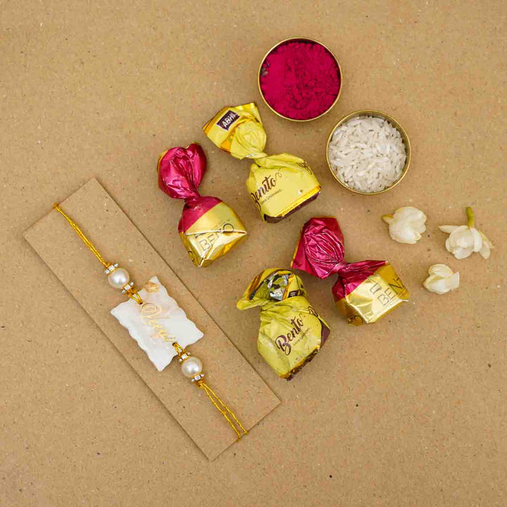 Personalized Handmade White Resin Rakhi With Roli Chawal - Flat Lay with Chocolates