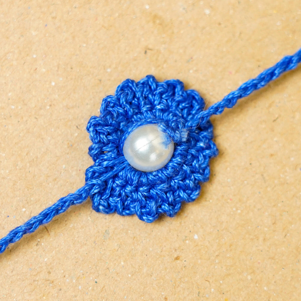 Handmade Crochet Round Pearl Cotton Rakhi With Roli Chawal - Close-up of blue centerpiece