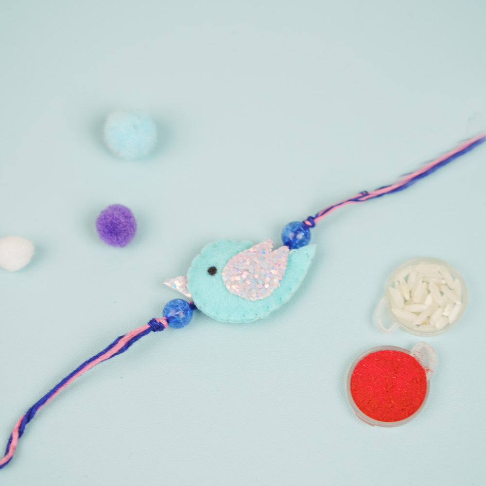 Handmade Blue Bird Theme Felt Kids Rakhi - Flat Lay with Decorative Items