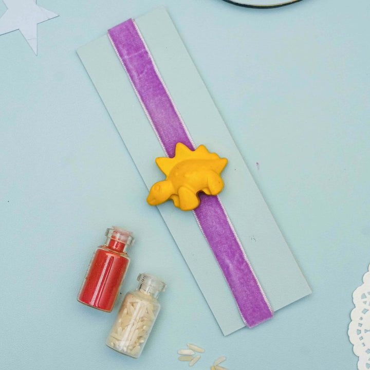 Handmade Dino Crayon Kids Rakhi With Roli Chawal - Flat lay with yellow dinosaur charm