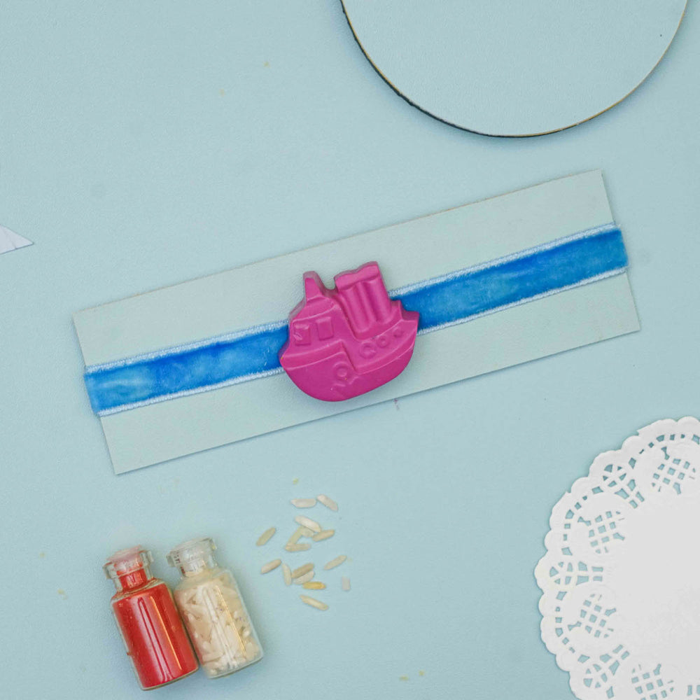 Handmade Ship Crayon Kids Rakhi With Roli Chawal - Full view of packaged bracelet with charm