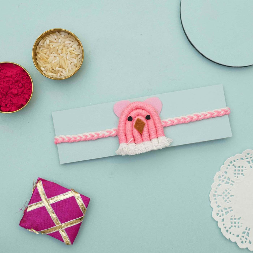 Handmade Macrame Pink Animal Design Cotton Kids Rakhi With Chocolates And Roli Chawal - Pink Bird Bracelet On Cardboard