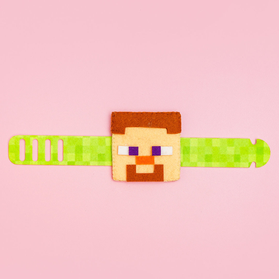 Handcrafted Minecraft Felt Rakhi For Kids With Roli Chawal - Laid Flat on Pink Surface