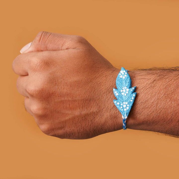 Handmade Ecofriendly Blue Feather Recycled Paper Rakhi With Roli Chawal - On wrist showing size fit