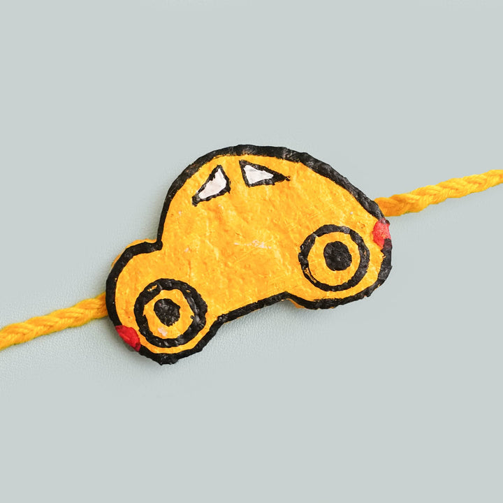 Handmade Ecofriendly Yellow Car Recycled Paper Rakhi With Roli Chawal - Close-up of Car Rakhi