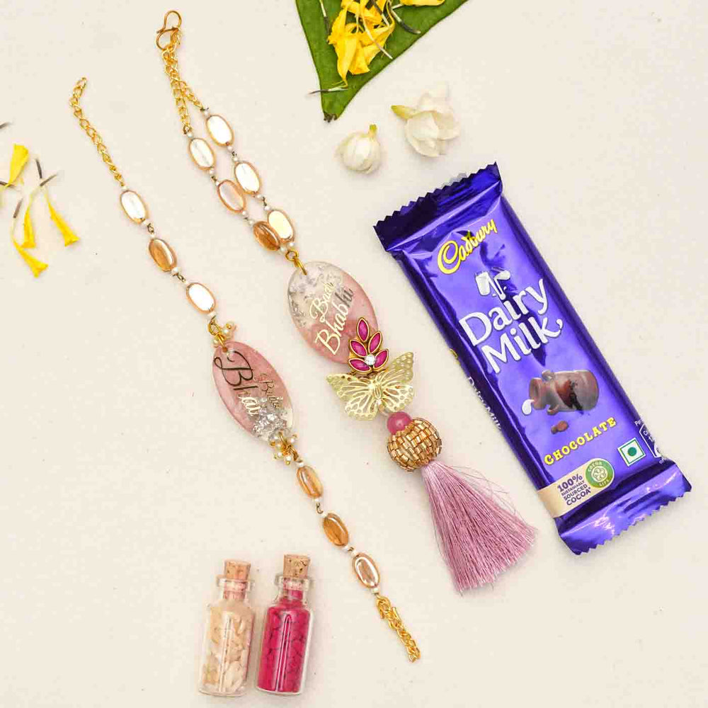 Handmade Resin Bada Bhai And Badi Bhabhi Rakhi With Chocolates And Roli Chawal Set Of 2 - Flat lay with chocolate bar and accessories