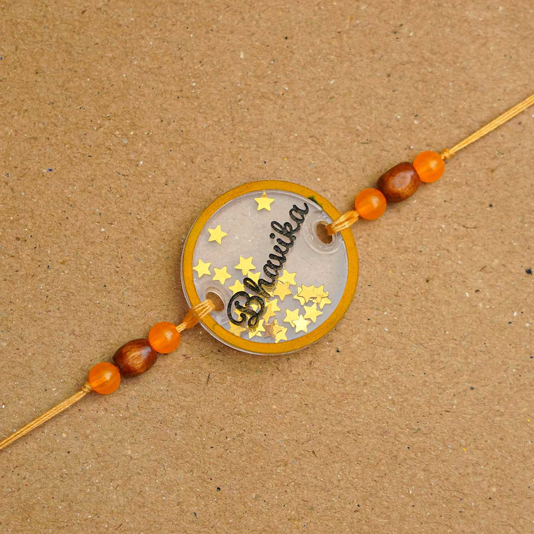 Personalized Handmade Round Glitter Acrylic Rakhi With Roli Chawal - Close-up of personalized name tag