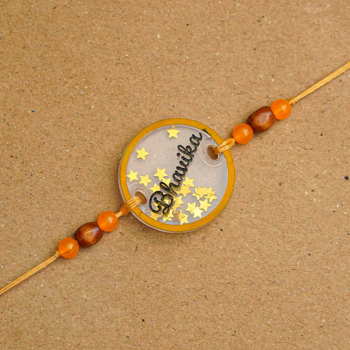 Personalized Handmade Round Glitter Acrylic Rakhi With Roli Chawal - Close-up of personalized name tag